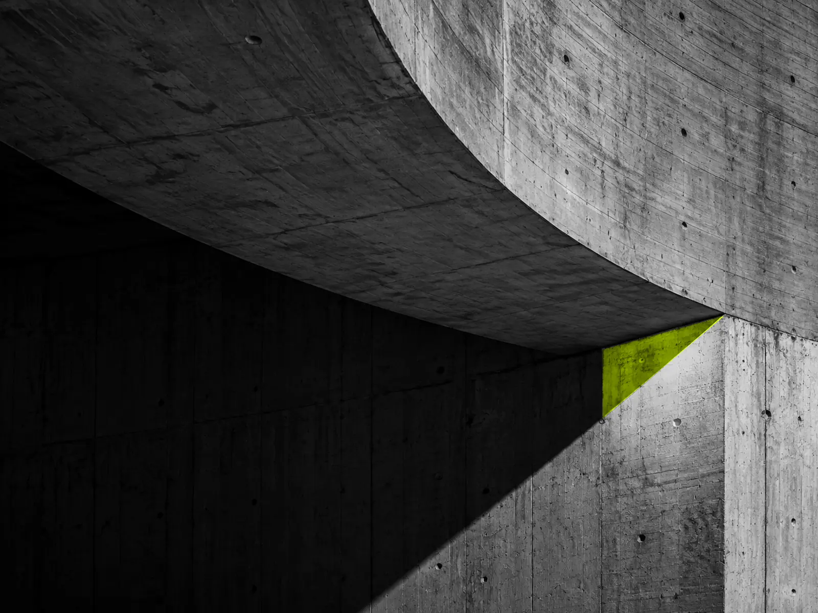 A sweeping curved concrete ceiling, with a wedge of fluoro-yellow light where it meets the wall.