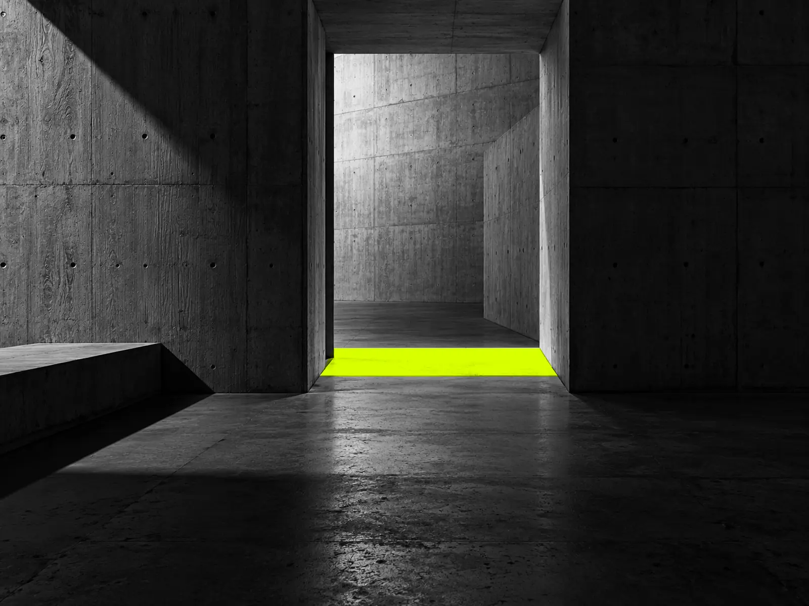 A dark concrete interior looking towards a doorway, with a rectangle of fluoro-yellow light on the threshold.