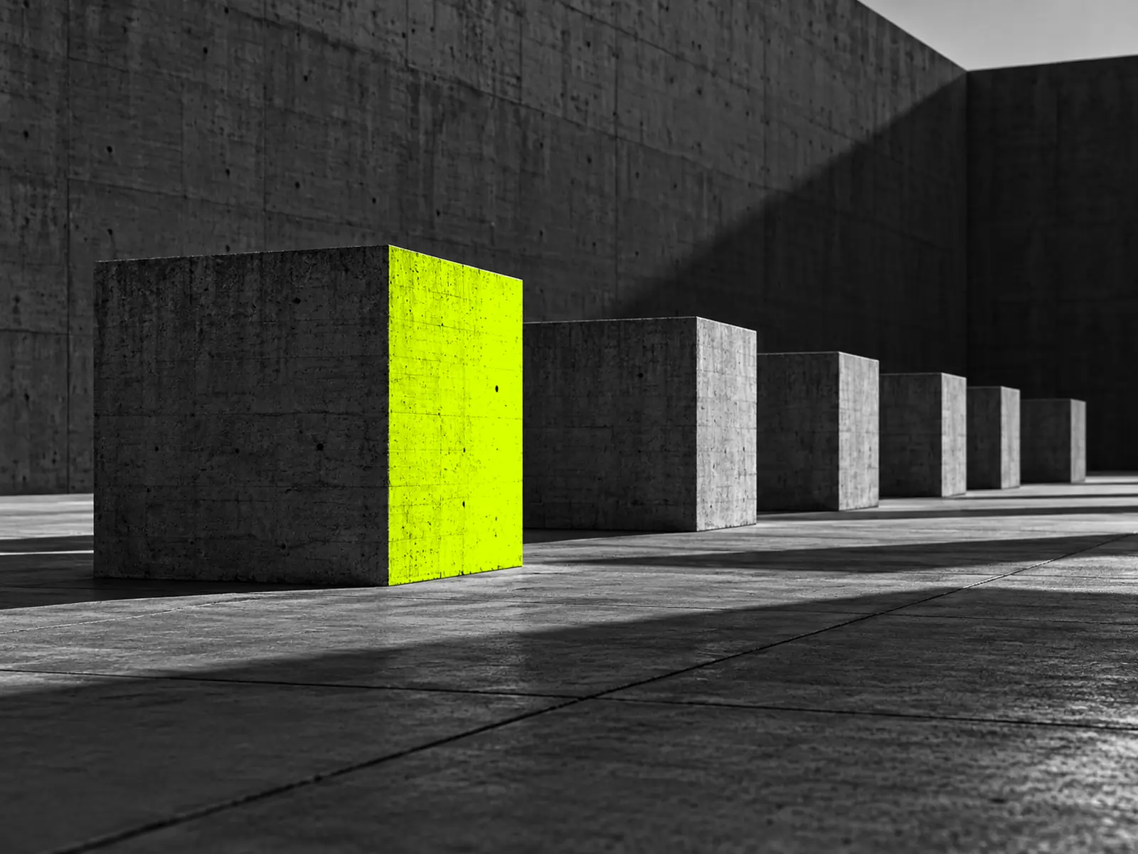 A row of identical concrete blocks in low sun; only the nearest catches fluoro-yellow light.