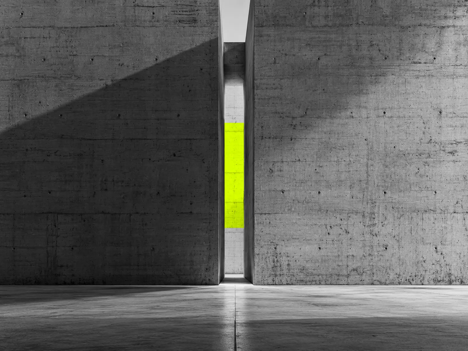 Two massive concrete walls almost meeting, with a narrow slit of fluoro-yellow light between them.