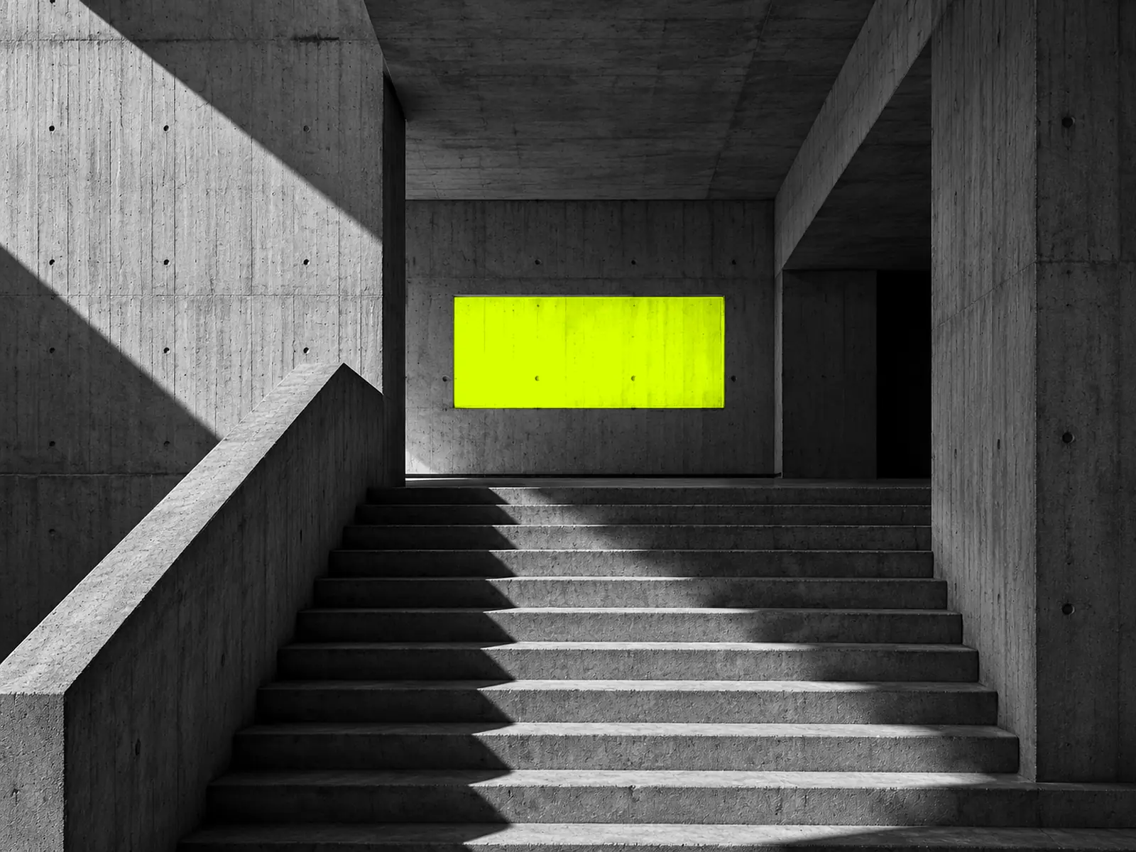 Concrete steps rising to a landing, with a rectangle of fluoro-yellow light on the wall like a screen.